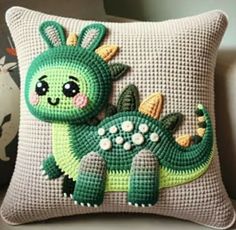 a green and white pillow with a small stuffed animal on it's back, sitting on a couch