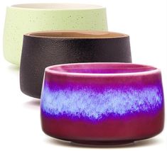 three different colored bowls sitting next to each other