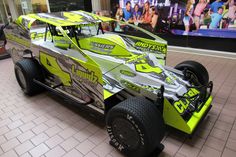 a yellow and black race car on display in a building