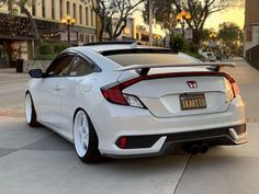 the rear end of a white honda civic hatchback parked in front of a building