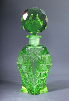 a green glass perfume bottle sitting on top of a table