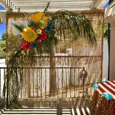 an arrangement of flowers is hanging on the side of a fenced in porch area