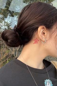 a woman with her hair in a bun and tattoos on her left side of her neck