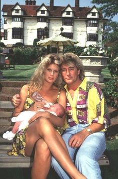 a man and woman sitting on a bench holding a baby