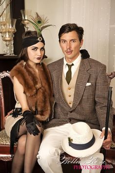 a man and woman sitting on a chair in fancy clothing posing for a photo together