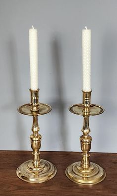 two brass candlesticks sitting on top of a wooden table