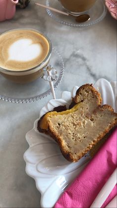 a piece of bread sitting on top of a white plate next to a cup of coffee