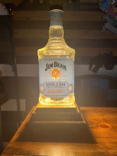 a bottle of j m beam double oak whiskey sitting on a wooden table in the sun