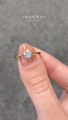 a woman's hand holding an engagement ring with a diamond on the middle finger