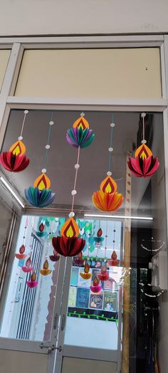 colorful paper flowers hanging from the ceiling in front of a store window with glass doors