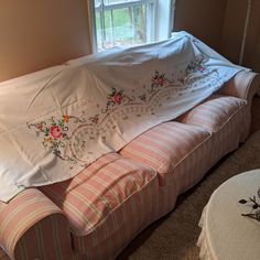 the couch is covered with white and pink striped fabric, which has flowers on it