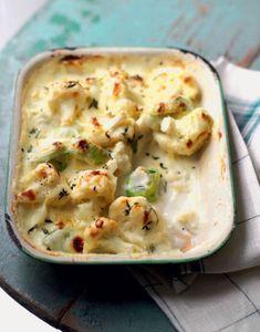 a casserole dish with broccoli and cauliflower in it on a table