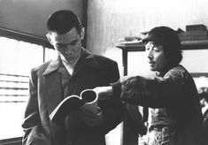 black and white photograph of two men looking at something on a table in front of them