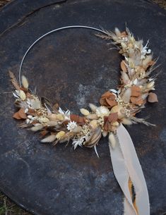 a wreath made out of dried flowers and feathers sitting on top of a stone slab