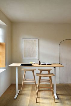 a table with two stools in front of it and a painting on the wall