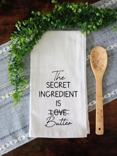 the secret ingredient is love butter on a tea towel next to a wooden spoon and green leaves