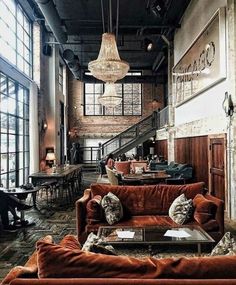 a living room filled with lots of furniture next to tall windows on the side of a building