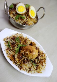 an egg and rice dish is served on a white plate with a silver serving bowl