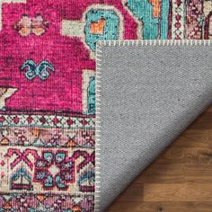 an area rug with various colors and patterns on the floor, including grey carpeting