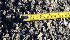 a measuring tape is laying on the ground next to some rocks and gravel that has been cut in half