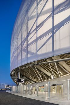 an empty parking lot in front of a large building with a white covering over it