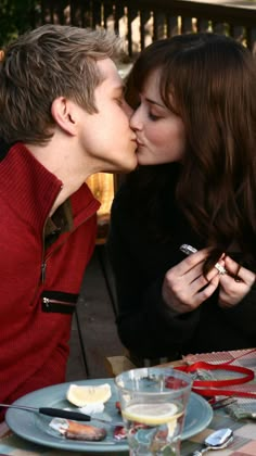 a man and woman kissing at an outdoor table