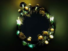 a wreath made out of pine cones is lit up with green and white light bulbs