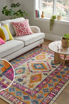 a living room with a white couch and colorful rug on the floor next to a window