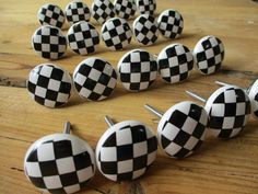 several black and white checkered buttons on a wooden table with pins in the shape of balls