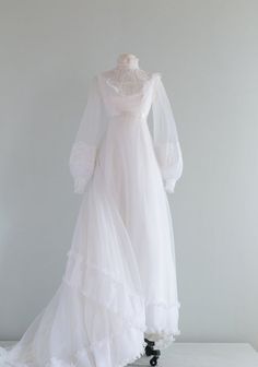 a white wedding dress on display against a gray background