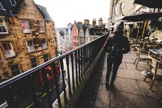 a woman is walking down the stairs in an alleyway with tables and chairs on either side