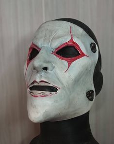 a white mask with red and black markings on it