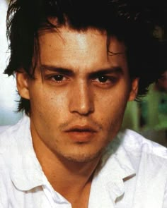 a close up of a person wearing a white shirt and looking at the camera with a serious look on his face