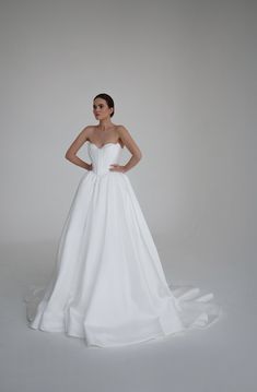 a woman in a white wedding dress posing for the camera with her hands on her hips