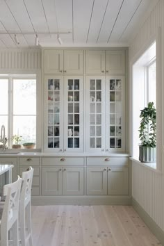 a kitchen with white cabinets and wooden floors, along with a dining room table in the center