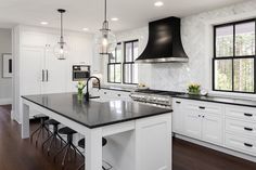 a large kitchen with white cabinets and black counter tops, along with dark wood flooring