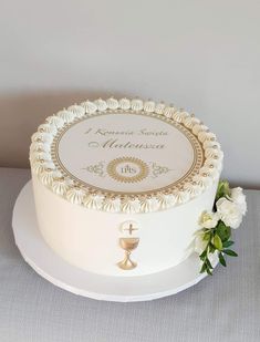 a wedding cake with white flowers on the top and gold trimmings around it