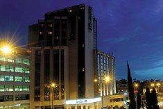 the building is lit up at night with street lights and cars parked in front of it