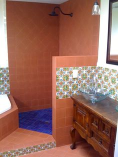 a bathroom with orange and blue tiles on the walls, sink and shower stall area