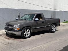 the truck is parked on the side of the road by the wall with no one in it