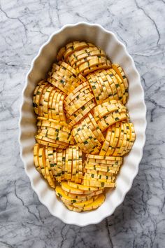 a white bowl filled with potatoes on top of a marble counter