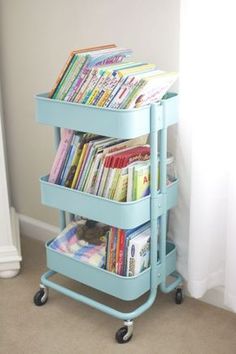 a blue cart with books on it in front of a window