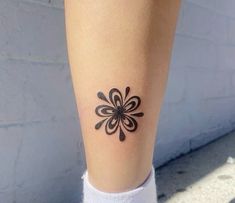 a woman's leg with a tattoo on it that looks like an abstract flower