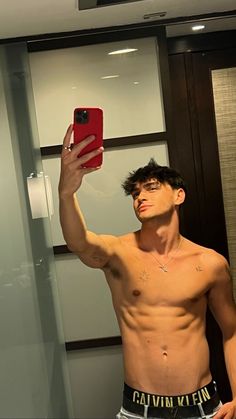 a shirtless man taking a selfie in front of a mirror with his cell phone