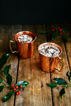 two copper mugs filled with hot chocolate and sprinkled with cranberries