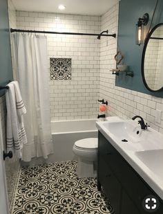 a bathroom with black and white tiles on the floor, shower curtain, toilet and sink