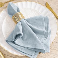 the napkins are folded on top of each other with gold rings at the end