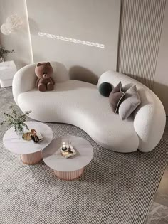 a white couch sitting in the middle of a living room next to two tables and a teddy bear