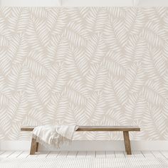 a wooden bench sitting in front of a wall with a white leaf pattern on it