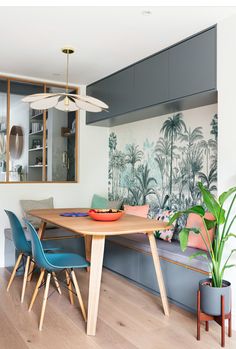 a dining room table with blue chairs and a wall mural in the backround